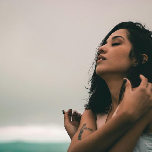 Mujer abrazandose a sí misma con expresión de calma y conexión emocional.