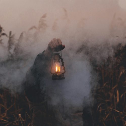 "Persona caminando entre la niebla con un farol encendido, representando la gestión de la incertidumbre emocional"